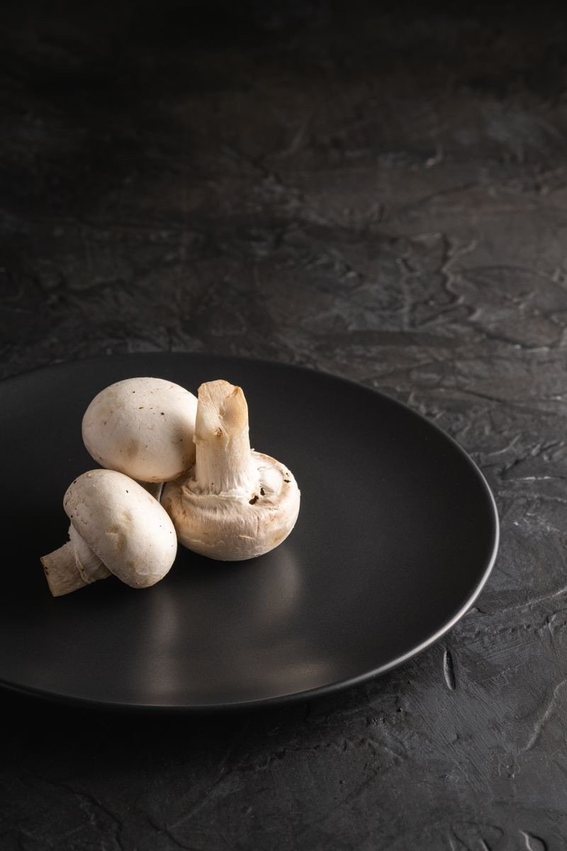 Champiñones enteros sobre un plato de cerámica negra.
