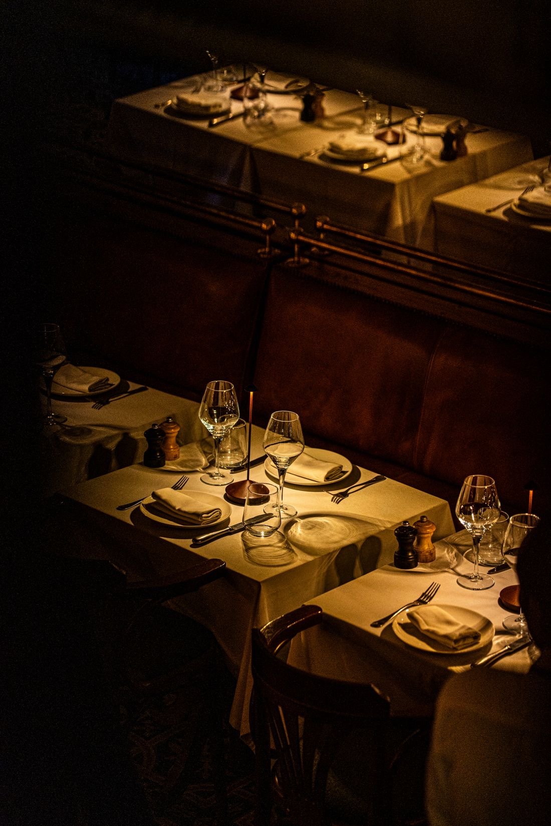 Mesas vestidas con mantel y copas bajo una luz dorada.