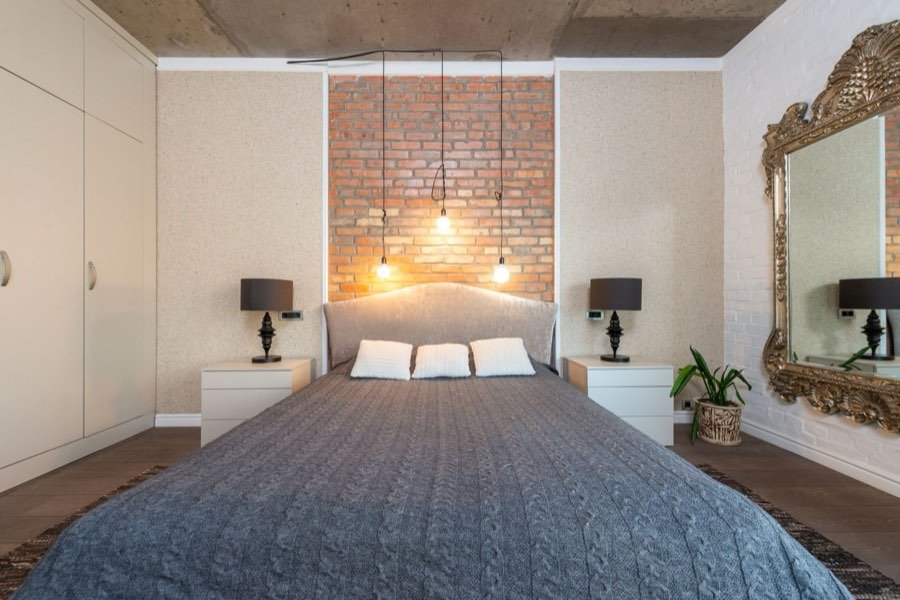 Habitación con pared de ladrillo visto y cama de lino.