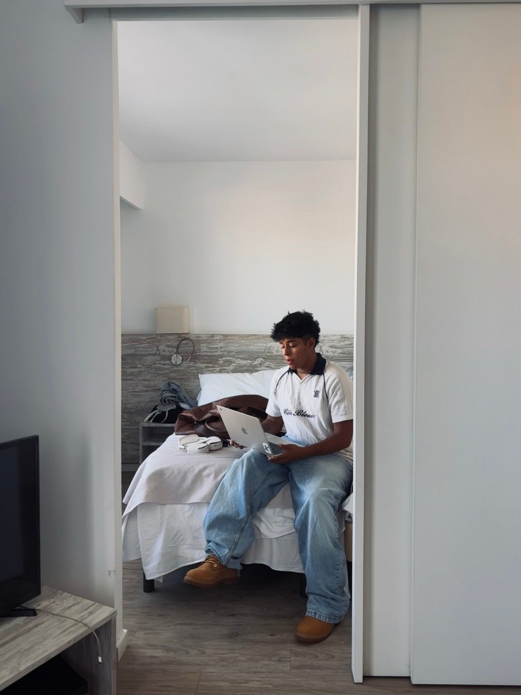 Persona del equipo de PAGINAS S trabajando con un portátil sentada en una cama de una habitación luminosa.